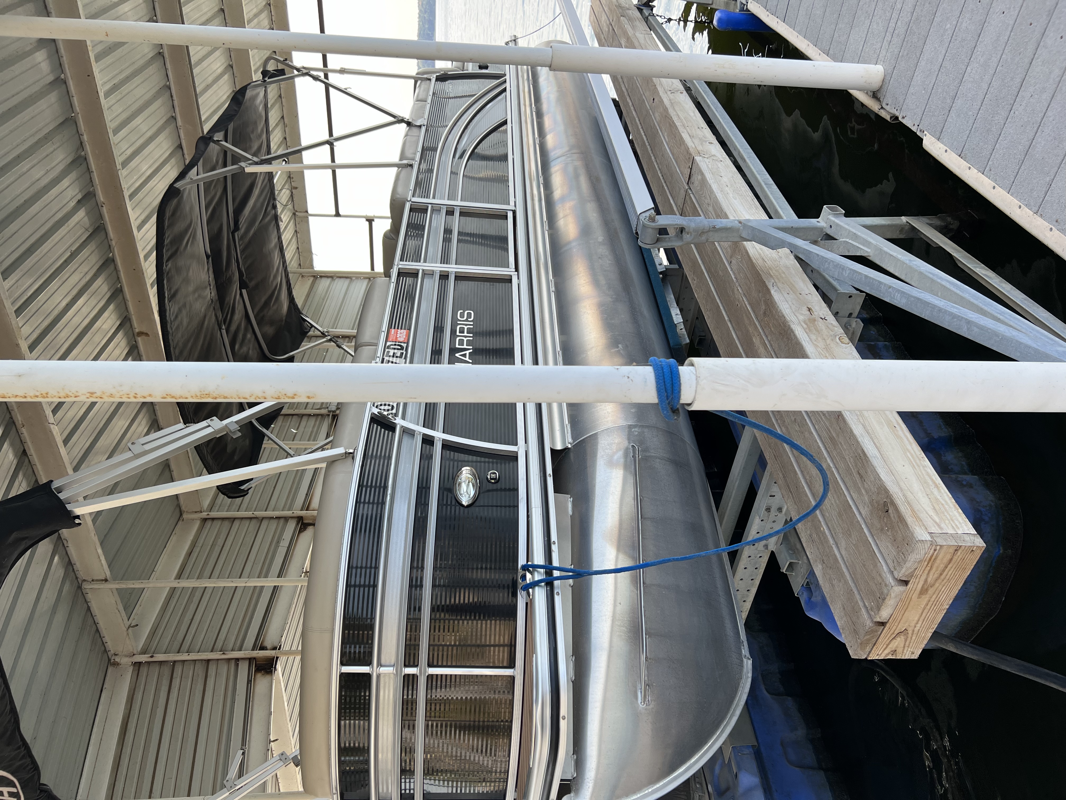 Detailed black and silver Harris tritoon on a lift under a covered slip